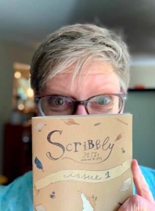 Canadian Scribbly writer Eira Braun-Labossiere holding her copy of Scribbly volume 1 in front of her face. Eyes peeking over the top.